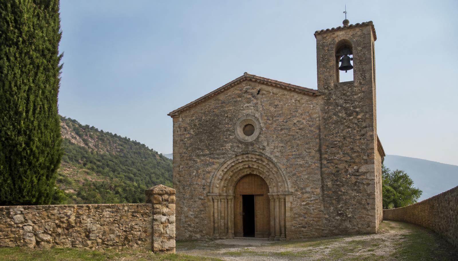 Iglesia rural de piedra con portada románica y campanario