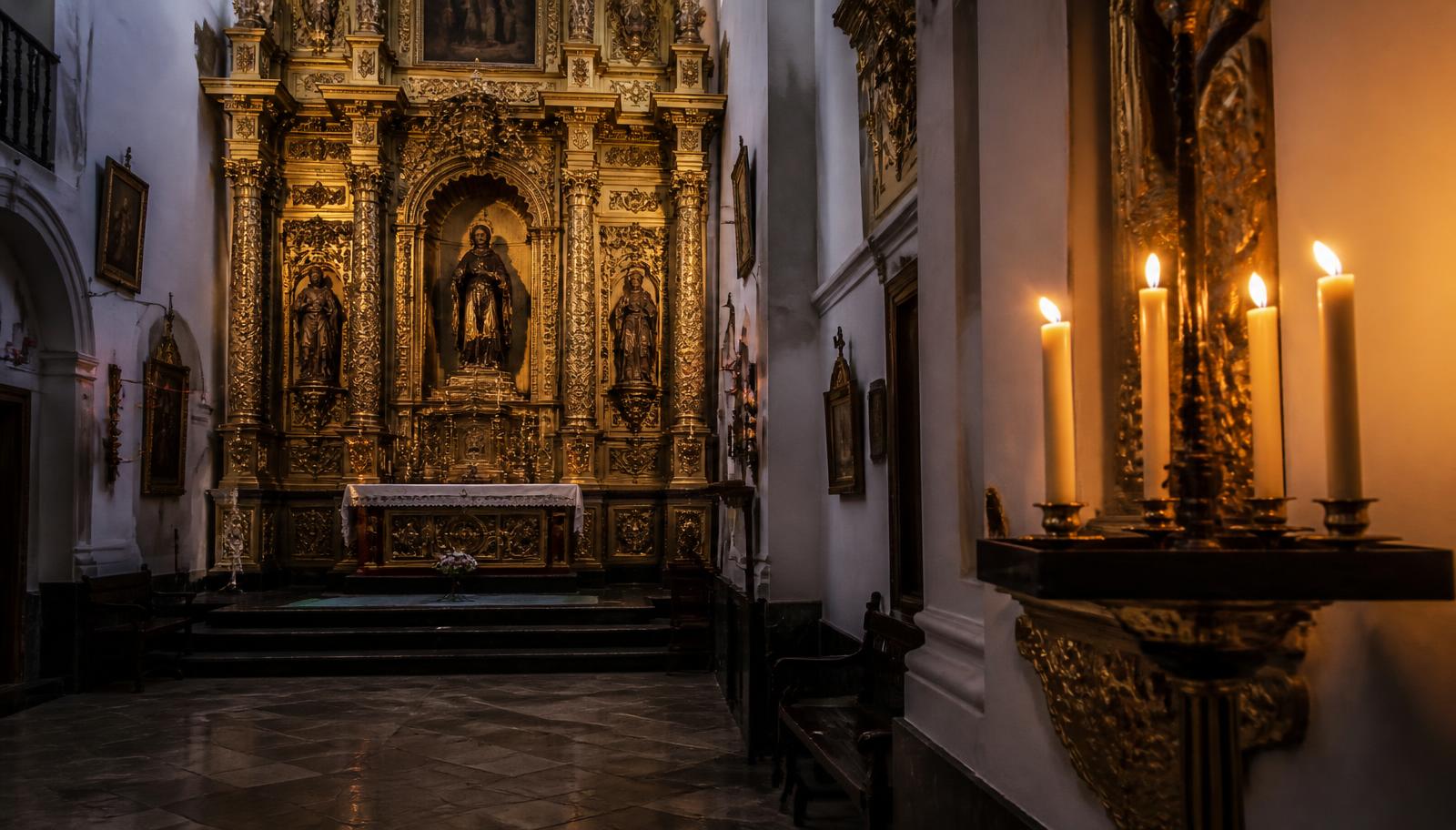 Interior barroco de una pequeña iglesia conventual con retablo dorado y velas encendidas