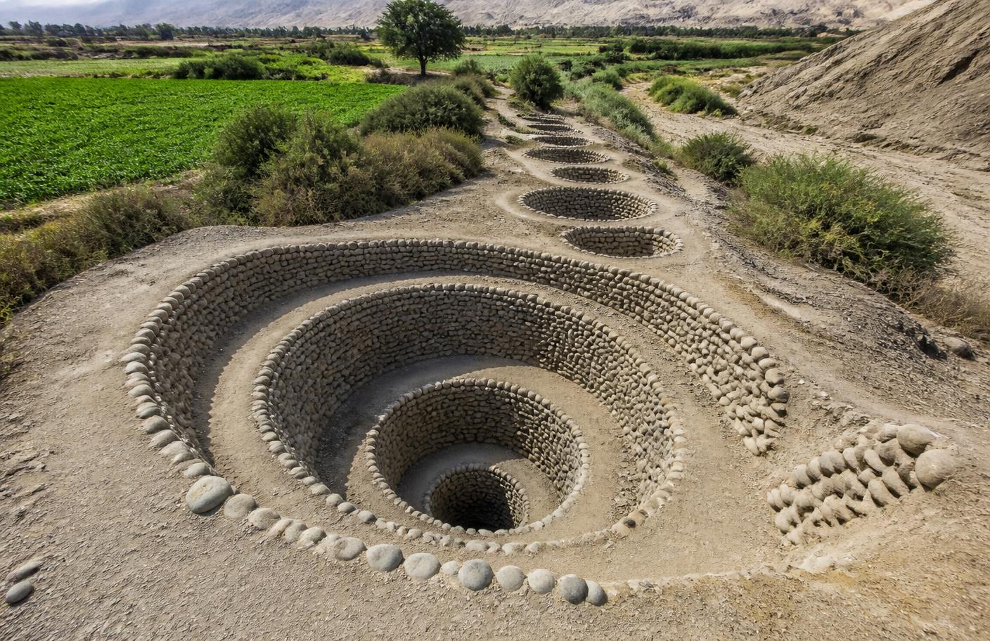 Pozos en espiral de piedra de los acueductos de Cantalloc, junto a campos verdes