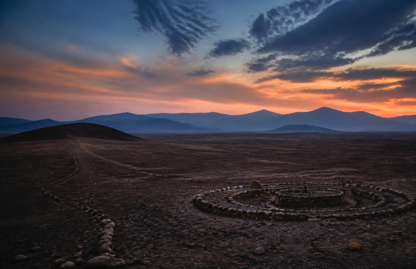 Paisaje desértico del sur del Perú al atardecer, con líneas de piedras sobre el terreno
