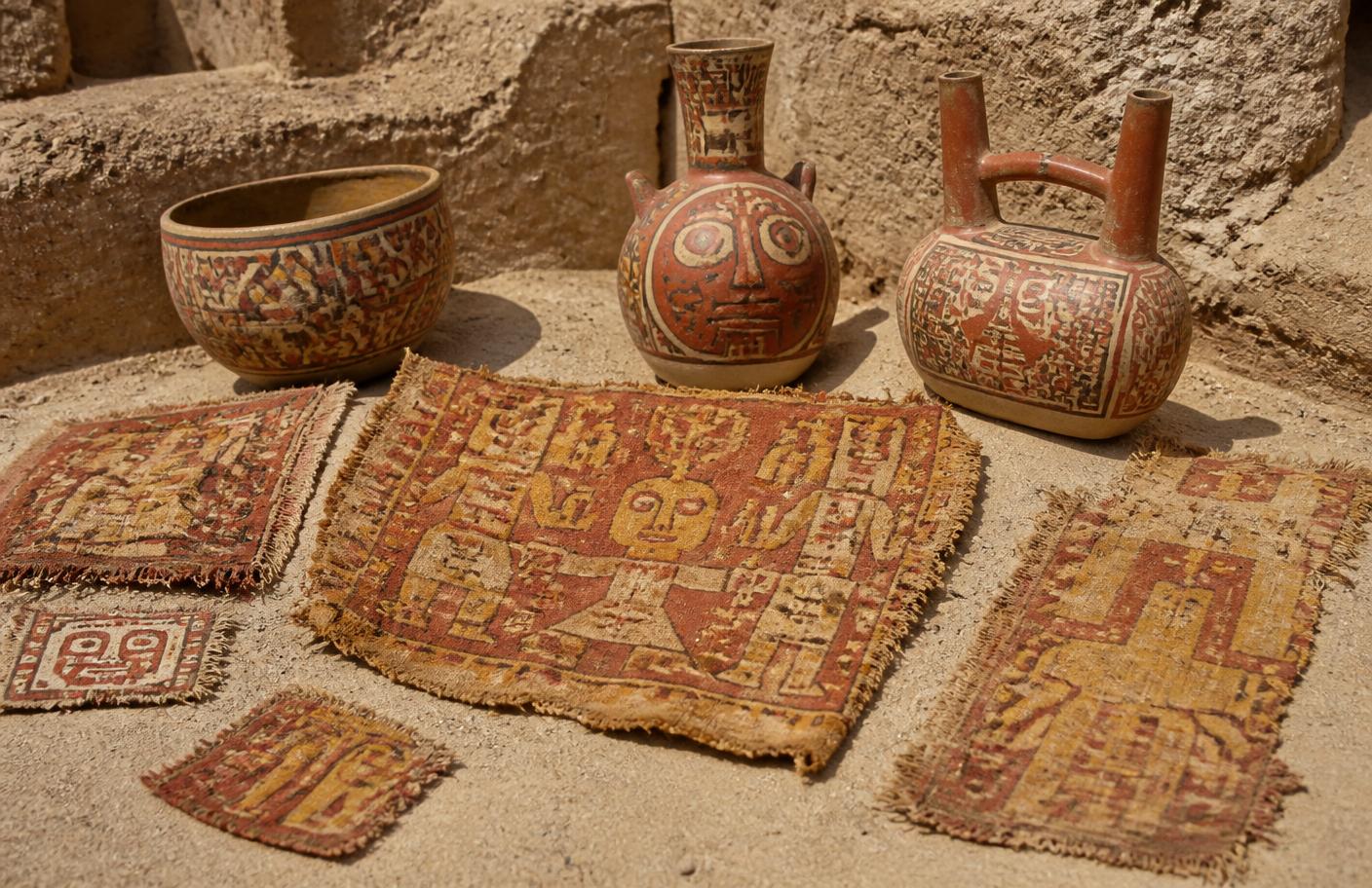 Textiles y cerámica policroma nasca sobre la arena de un sitio arqueológico